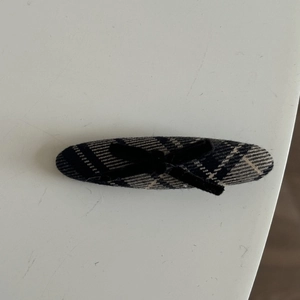 Detail of blue plaid fabric hair clip with a black velvet bow in a preppy style