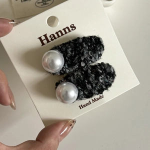 Détail de barrettes à cheveux en tweed avec perles blanches sur carte de présentation