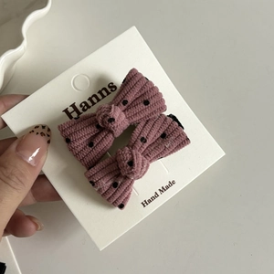 Gros plan de barrettes à cheveux en velours côtelé rose à pois noirs sur carte à main
