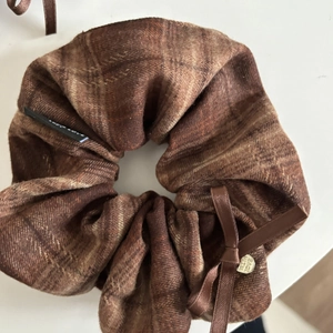 Detail of coffee plaid scrunchie with silk bow and heart pendant featuring With Love engraving