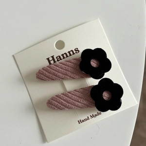 Détail de barrettes en velours rose avec fleurs noires sur carte de présentation