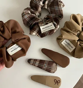 Flat lay of vintage brown plaid scrunchies and embroidered bow hair clips set