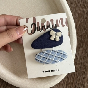 Detail of handmade fabric hair clips in blue and checkered patterns on card