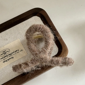 Gros plan sur la pince à cheveux en peluche marron avec ressort doré sur un plateau