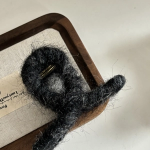 Vue détaillée d'une pince à cheveux en peluche gris foncé avec ressort en métal doré