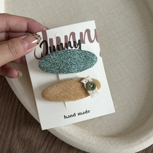 Detail of tweed and corduroy hair clips with lace trim and buttons on a display card