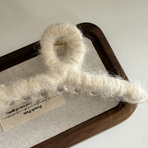 Détail d'une pince à cheveux en peluche crème avec esthétique française sur plateau