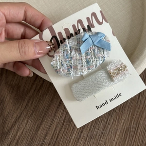 Detail of blue tweed bow clip and silver glitter hairpin on a handmade display card