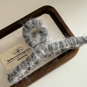 Détail de la grande pince à cheveux en peluche grise avec ressort en métal doré sur bois