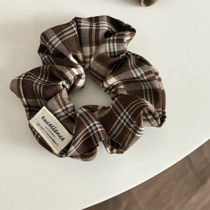 Close-up of brown plaid scrunchie fabric texture with vintage embroidery detail