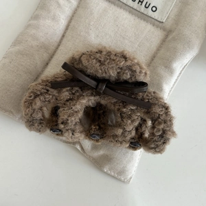 Detailed close-up of plush brown shark hair claw with leather bow knot and sturdy black teeth