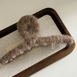 Gros plan détaillé d'une pince à cheveux en peluche marron sur un plateau en bois
