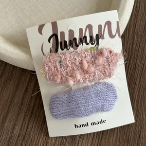 Detail of pink plush and purple knitted hair clips set on original display card
