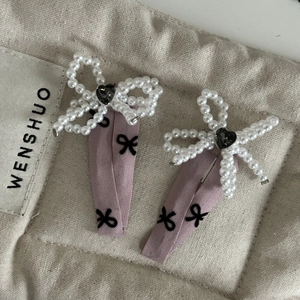 Elegantes Paar rosa Schleifen-Haarspangen mit Perlen und schwarzen Herzsteinen auf Segeltuch