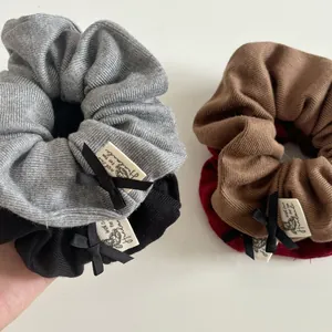 Detail of four knitted hair scrunchies with ribbons and handmade cotton tags