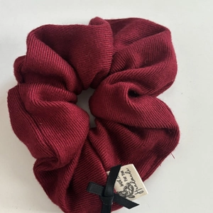 Detail of burgundy knitted scrunchie with black bow and handmade fabric label