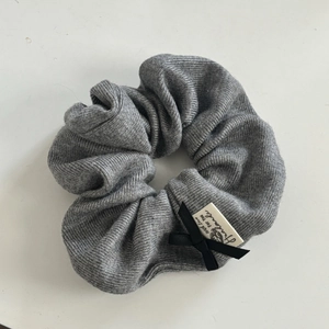 Detail of grey knitted hair scrunchie with black bow and handmade fabric label