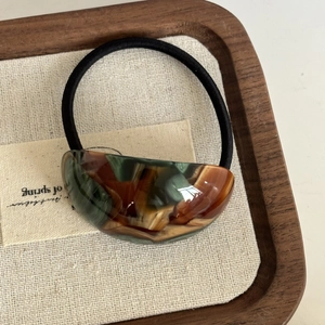 Dettaglio dell'elastico per capelli in acetato marmorizzato verde con trama ambra vintage