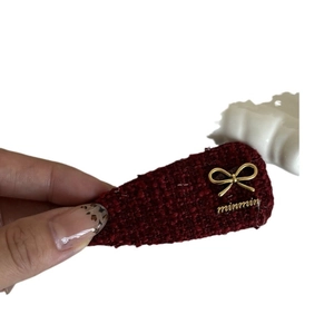 Elegant reddish-brown tweed hair clip with gold metal bow and lettering detail