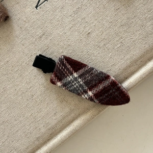 Vue détaillée d'une pince à cheveux en tissu écossais rouge et gris avec base mate noire