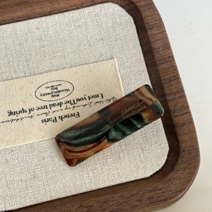 Dettaglio del fermaglio rettangolare in acetato con scritta dorata France Handmade