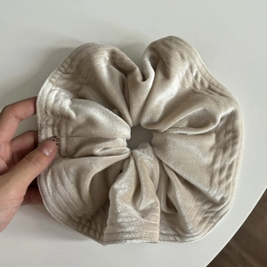Macro shot of oversized champagne velvet scrunchie with soft pleated texture
