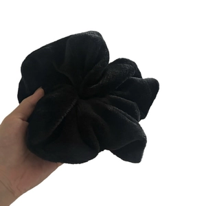 Oversized plush black scrunchie made of soft velvet material for ponytail hairstyles