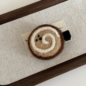 Détail d'une pince à cheveux en feutre de laine faite main au design de biscuit brun