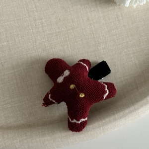 Gros plan détaillé d'une pince à cheveux bonhomme pain d'épices en tricot bordeaux