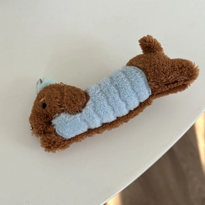 Détail de la pince à cheveux chien en peluche avec fourrure bouclée brune et accent bleu