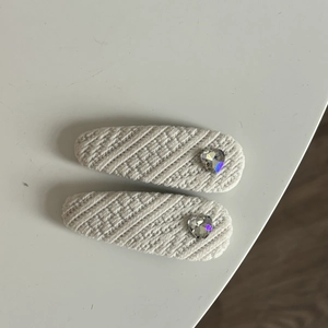Gros plan de barrettes à cheveux en tricot beige avec cristaux en forme de cœur