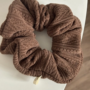 Détail d'un chouchou en tricot marron avec texture côtelée et petite étiquette latérale