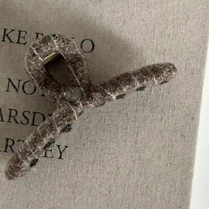 Detailed close-up of a brown tweed hair claw clip with a silver crystal heart