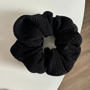 Détail d'un chouchou noir en velours côtelé avec texture douce et bande élastique