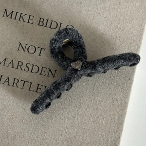 Elegant grey wool heart-shaped hair claw clip on a minimalist magazine background