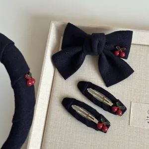 Detail view of navy fabric hair accessory set with red cherry ornaments and bows