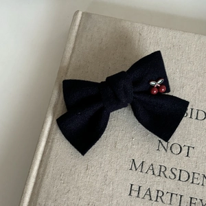 Detailed close-up of navy blue fabric bow hair clip with cute red cherry charms