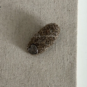 Detailed view of a brown tweed hair clip featuring a sparkling silver heart decoration