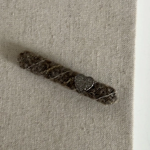 Detail of wool fabric hair clip featuring a sparkling rhinestone heart on brown textile