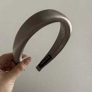 Detail view of champagne satin sponge headband featuring a woven HANDMADE label inside