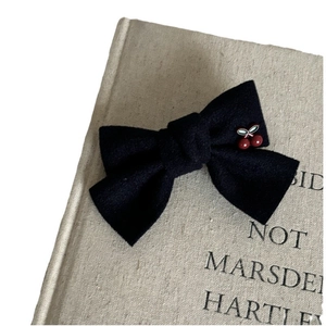 Navy blue velvet bow hair clip with red cherry detail on vintage book cover