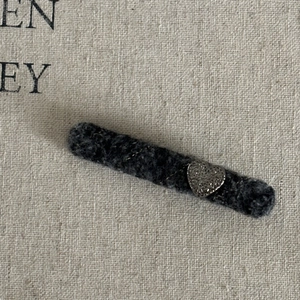Macro detail of charcoal grey wool felt hair clip with silver heart metal accent on canvas
