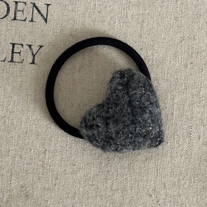 Detailed macro view of a brown heart-shaped woolen hair tie with elegant gold metallic threads