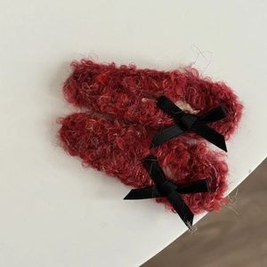 Detailed macro view of plush red hair clips with soft texture and black ribbon bows