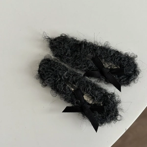 Close-up of black plush hair clips featuring soft faux fur and delicate silk ribbon bows