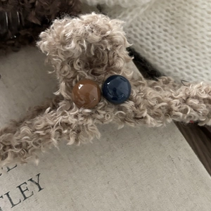 Dettaglio molletta per capelli in peluche con perline e morbida texture beige caldo