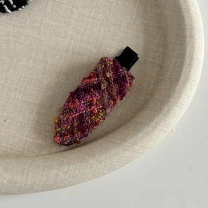 Gros plan sur une pince à cheveux en tweed français avec tissu tissé coloré sur plateau