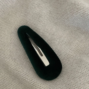 Dunkelgrüne Samt-Haarspange Snap-Clip auf einem beigen gestrickten Hintergrund