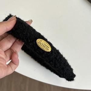 Schicker schwarzer Lammwoll-Haarreif mit ovalem Goldetikett für die Wintermode