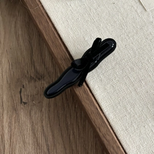 Elegant black acetate bow hair clip with glossy finish and satin ribbon detail